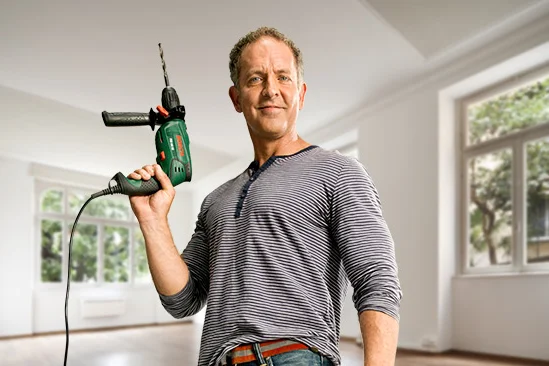 Person mit Bohrmaschine in einem Raum